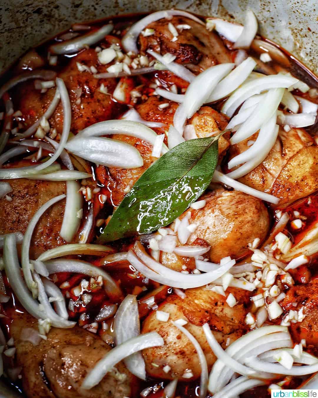 chicken-adobo-cooking-tip cooking chicken adobo with onions, garlic, and laurel leaves