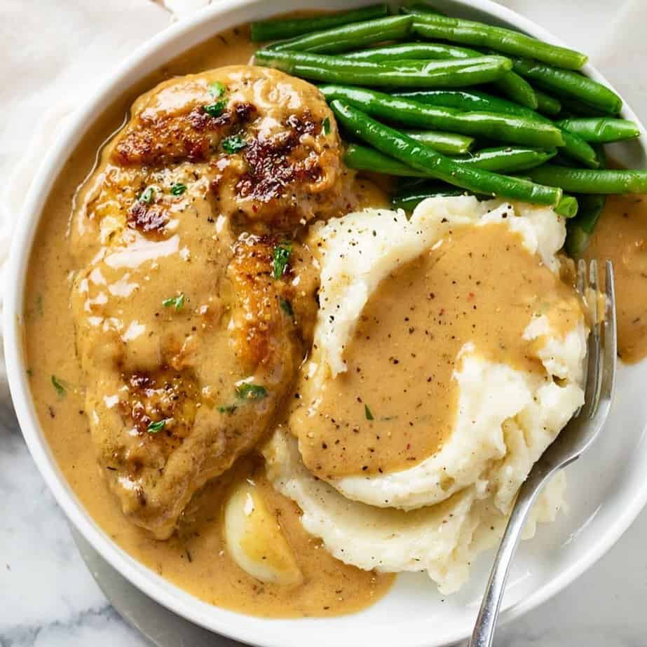 a serving of chicken thighs with mashed potatoes and green beans