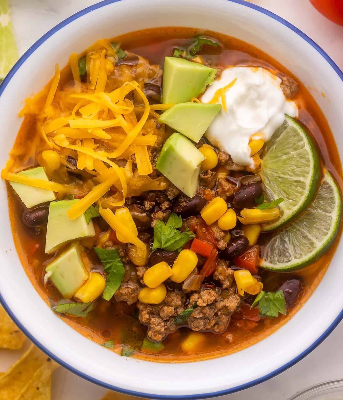 taco soup served with sour cream, lime, and avocados